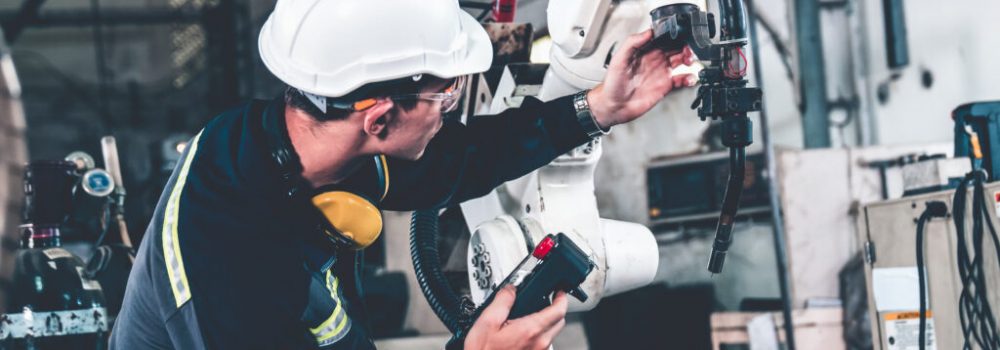 Young factory worker working with adept robotic arm